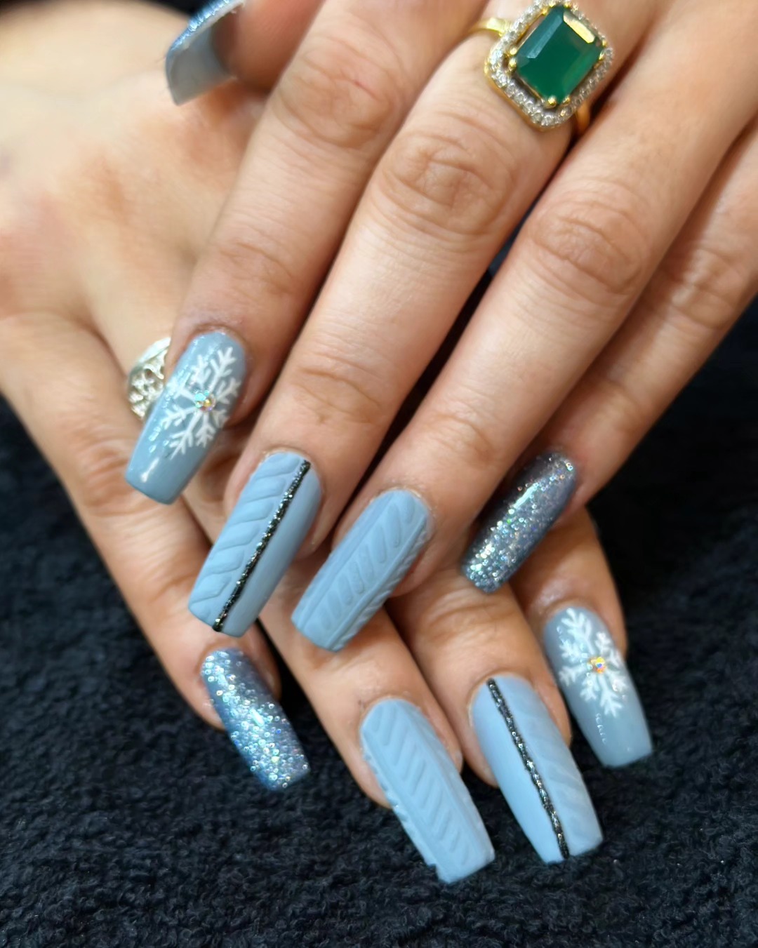 Powder-blue winter nail art with snowflake detailing and glitter accents